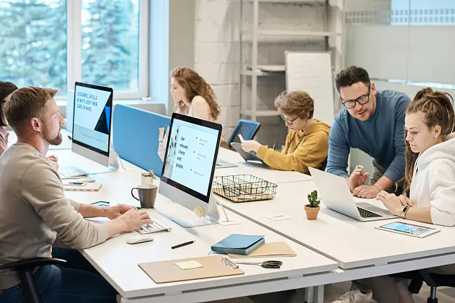 Gruppe junger Menschen mit Lehrer an Computerarbeitsplätzen