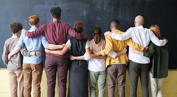 Gruppe von Leher*innen, die sich die Arme um die Schulter legen. 