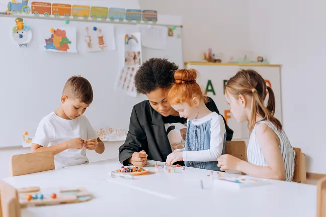 Pädagogische Fachkraft spielt mit drei Kindern